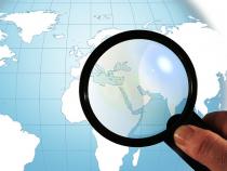 Magnifying glass over a globe.