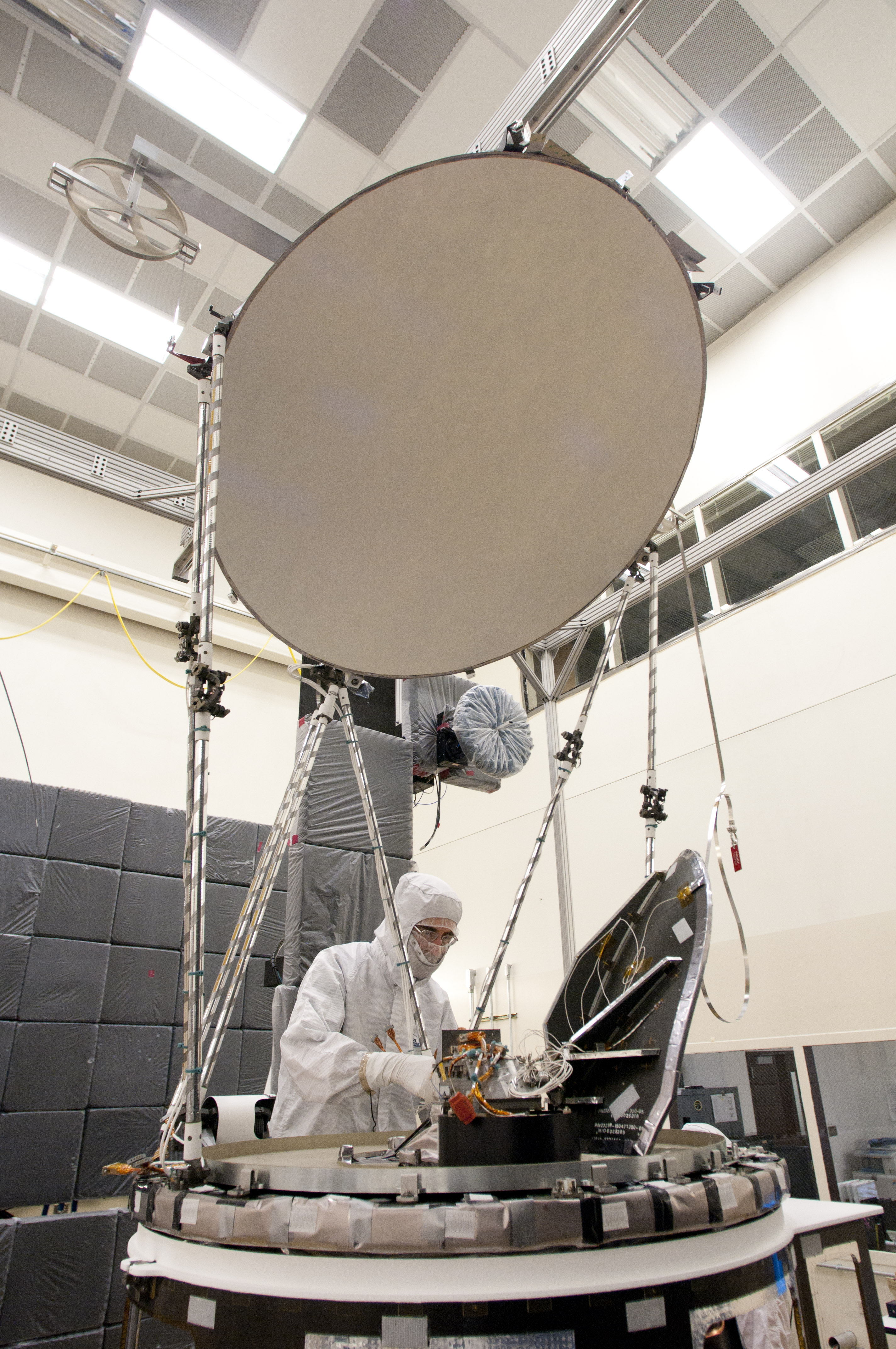 Engineer working on the GMI in a lab, with large reflictive dish in center.