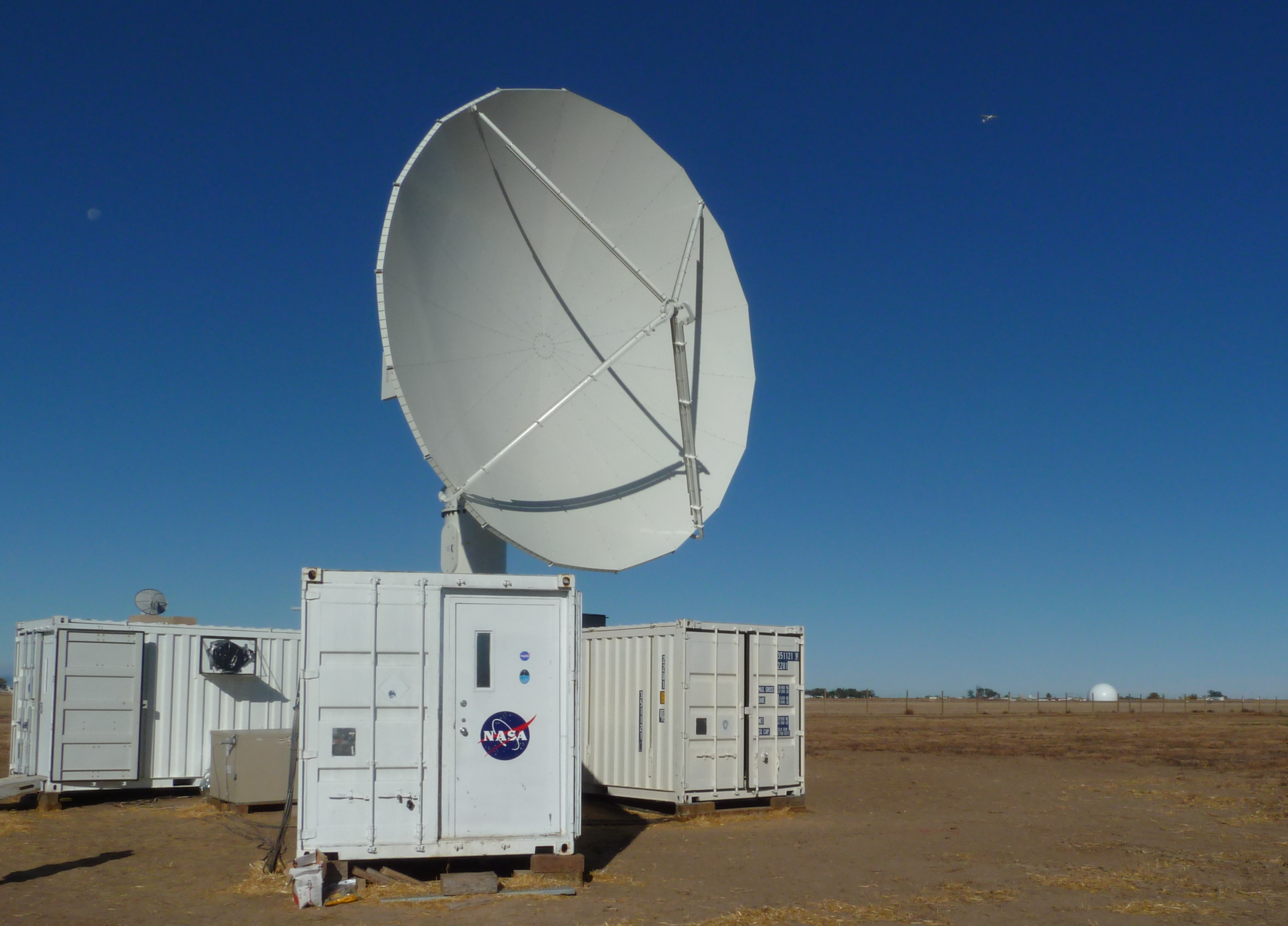 The NPOL instrument, a large circular radar dish under a blue sky