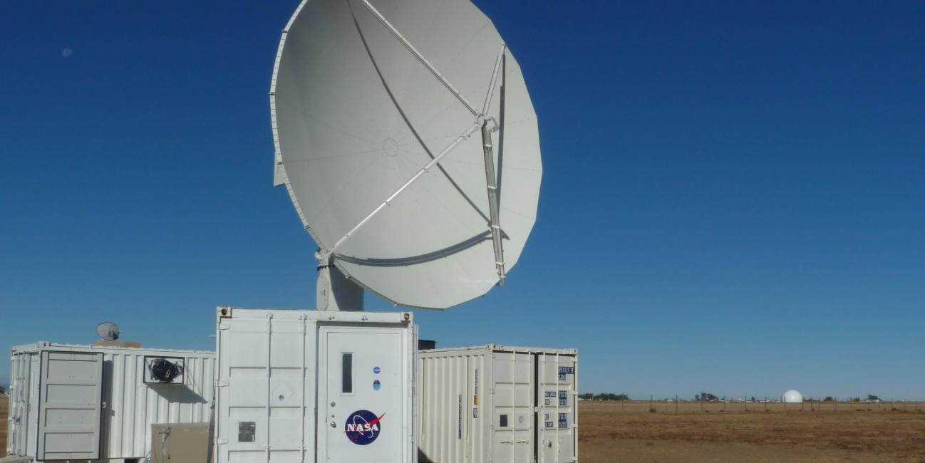 The NPOL instrument, a large radar dish attached to a trailer under a blue sky