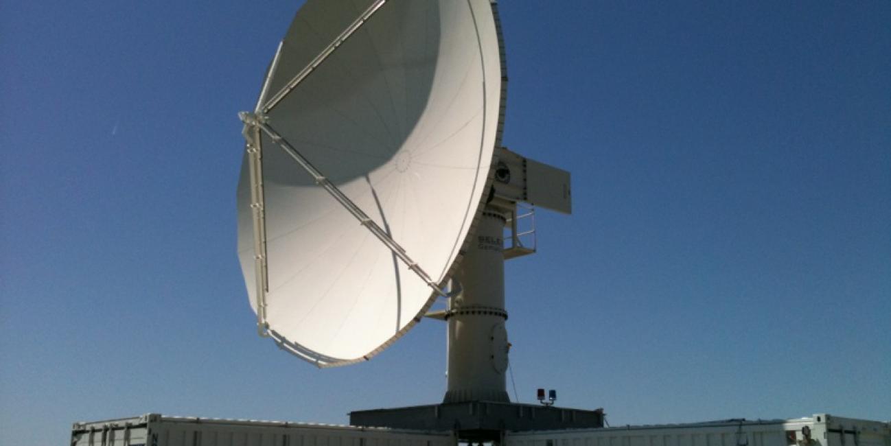 The NPOL instrument, a large radar dish attached to a trailer under a blue sky