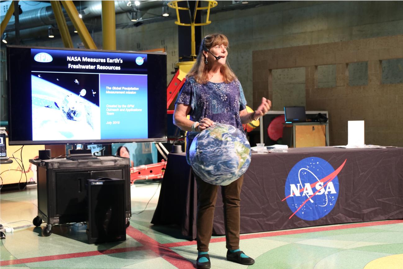 Dorian Janney stands in front of a NASA table holding a globe of Earth.